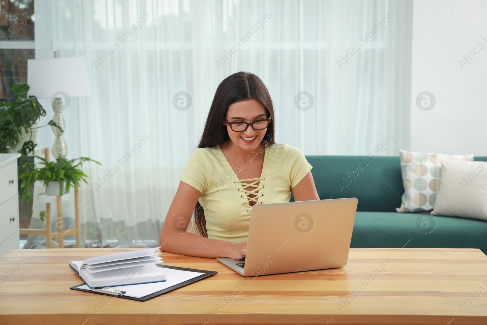 Photo of Young woman using laptop at table in living room. Internet shopping