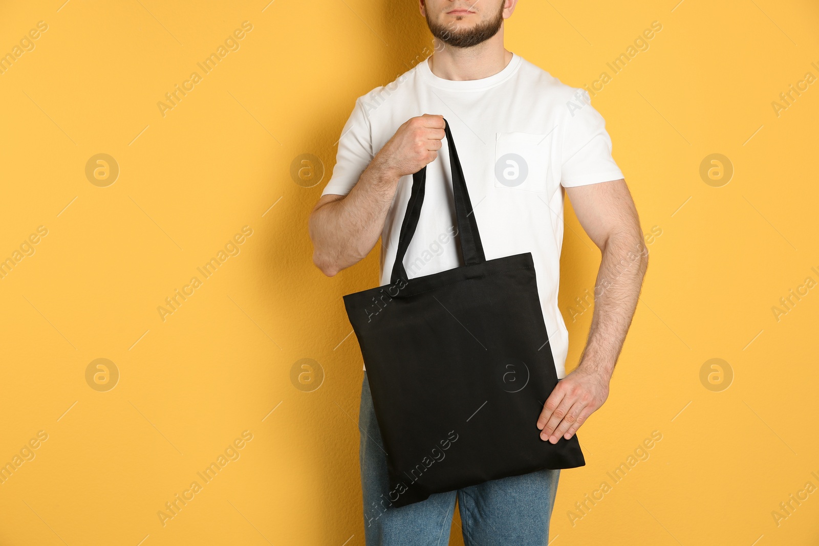 Photo of Man with cotton shopping eco bag on color background. Mockup for design