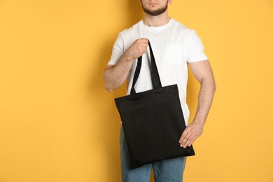 Photo of Man with cotton shopping eco bag on color background. Mockup for design