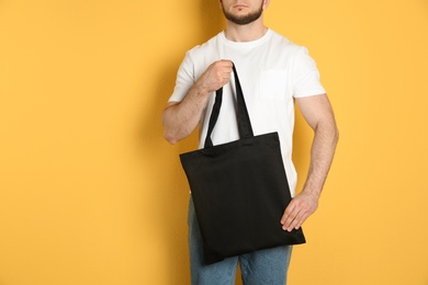 Man with cotton shopping eco bag on color background. Mockup for design