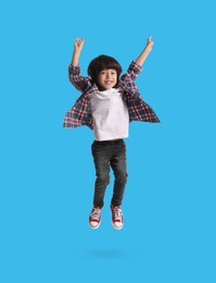 Image of Happy boy jumping on light blue background, full length portrait