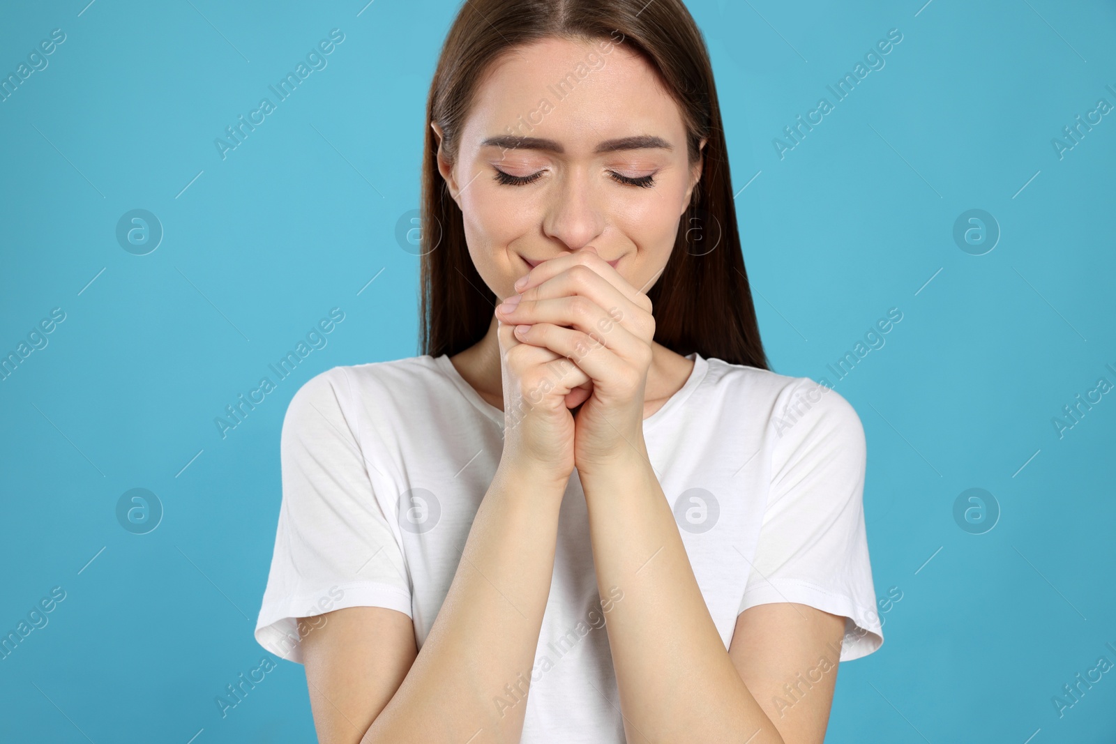 Photo of Woman with clasped hands praying on turquoise background