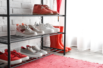 Shelving rack with stylish women's shoes near white brick wall indoors