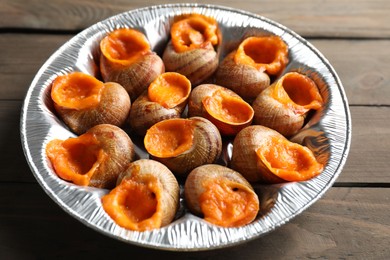 Photo of Delicious cooked snails on wooden table, closeup