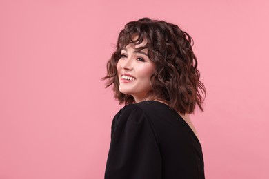 Portrait of beautiful young woman with wavy hairstyle on pink background. Space for text