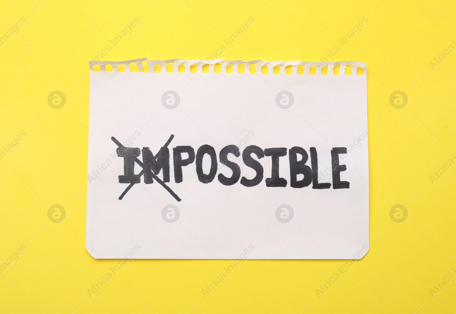 Photo of Motivation concept. Paper with changed word from Impossible into Possible by crossing over letters I and M on yellow background, top view