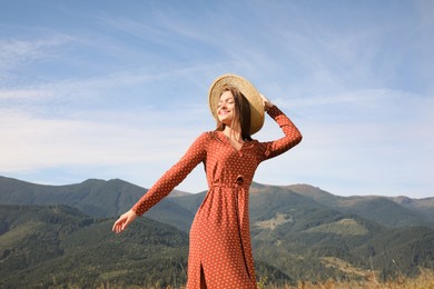 Photo of Young woman with straw hat walking in beautiful mountains on sunny day