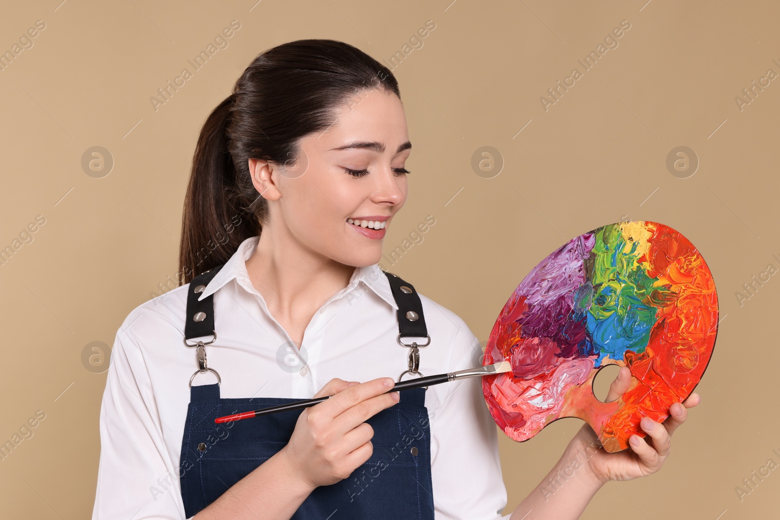Photo of Woman with painting tools on beige background. Young artist