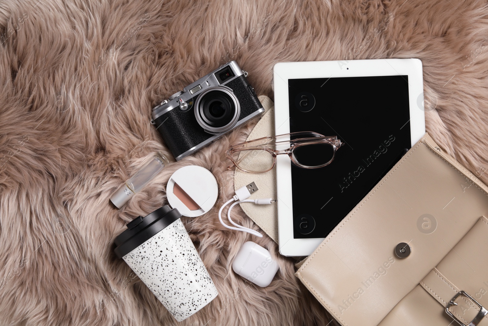 Photo of Stylish urban backpack and different items on brown faux fur, flat lay