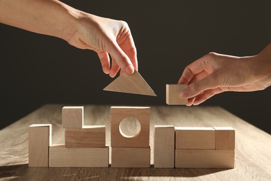 Photo of People constructing with wooden building blocks, closeup. Corporate social responsibility concept