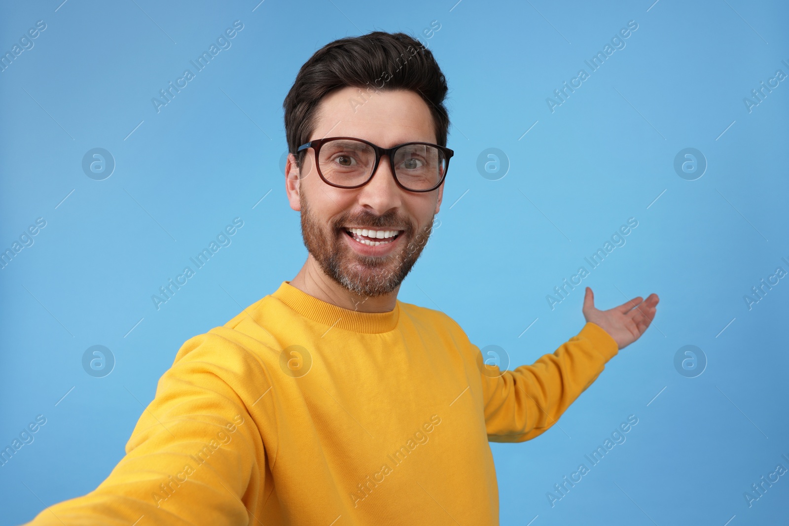 Photo of Smiling man taking selfie on light blue background