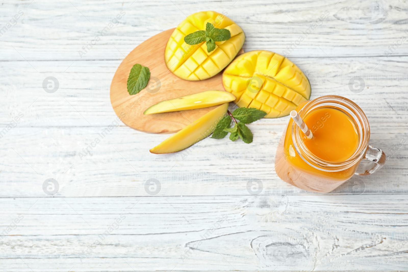 Photo of Fresh delicious mango drink on white wooden table, flat lay. Space for text