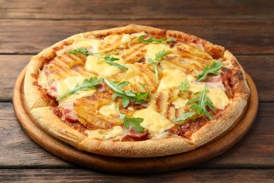 Photo of Delicious pineapple pizza with arugula on wooden table