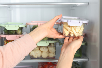 Woman taking container with frozen potato from refrigerator, closeup