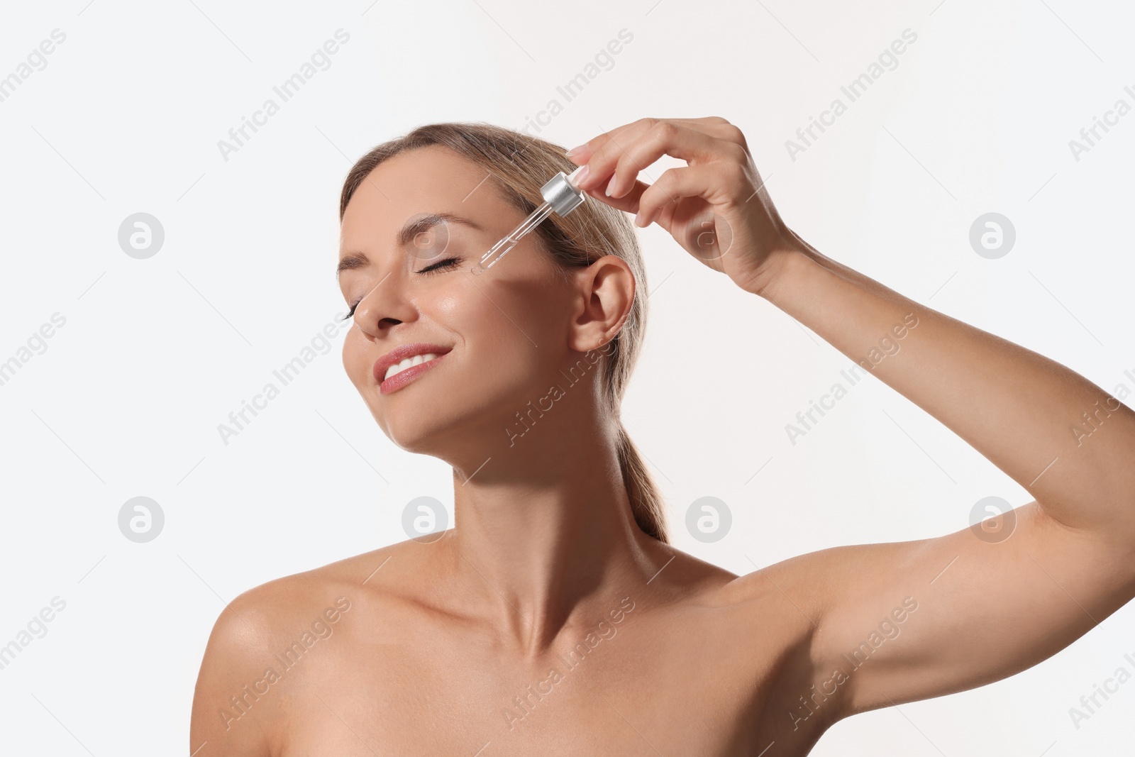 Photo of Beautiful woman applying cosmetic serum onto her face on white background