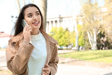 Young woman talking by phone outdoors on sunny day