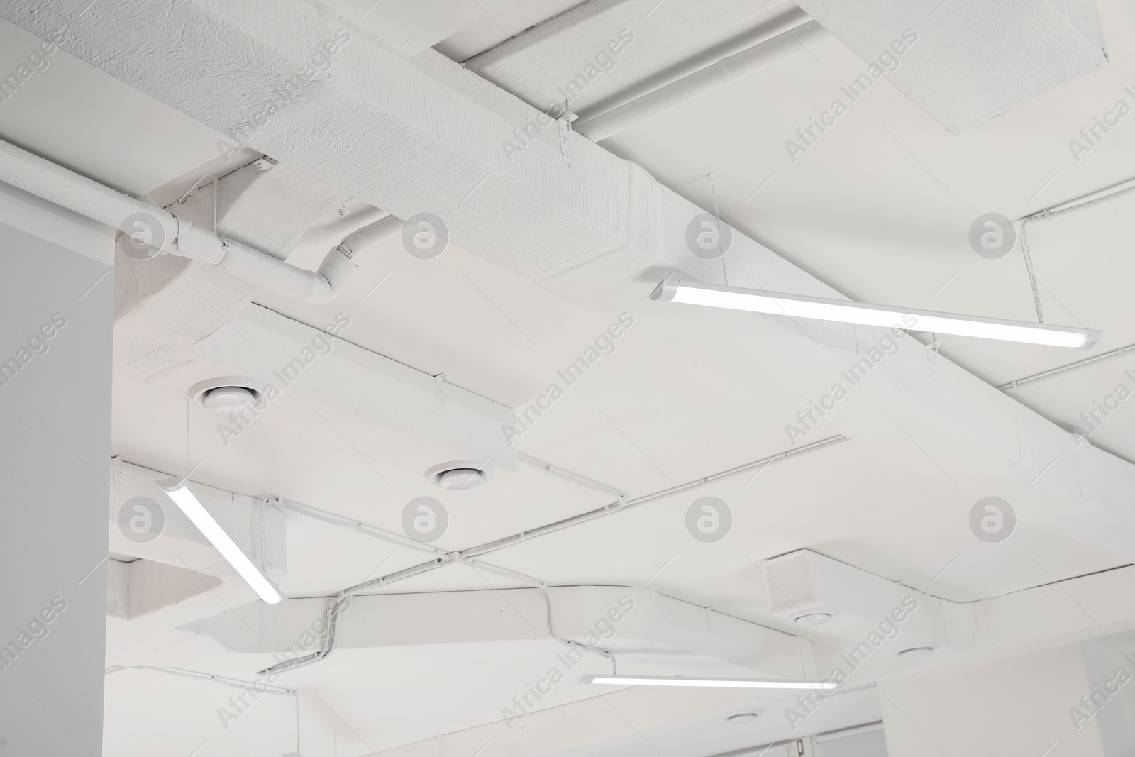 Photo of White ceiling with modern lighting in room, low angle view