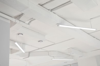 Photo of White ceiling with modern lighting in room, low angle view