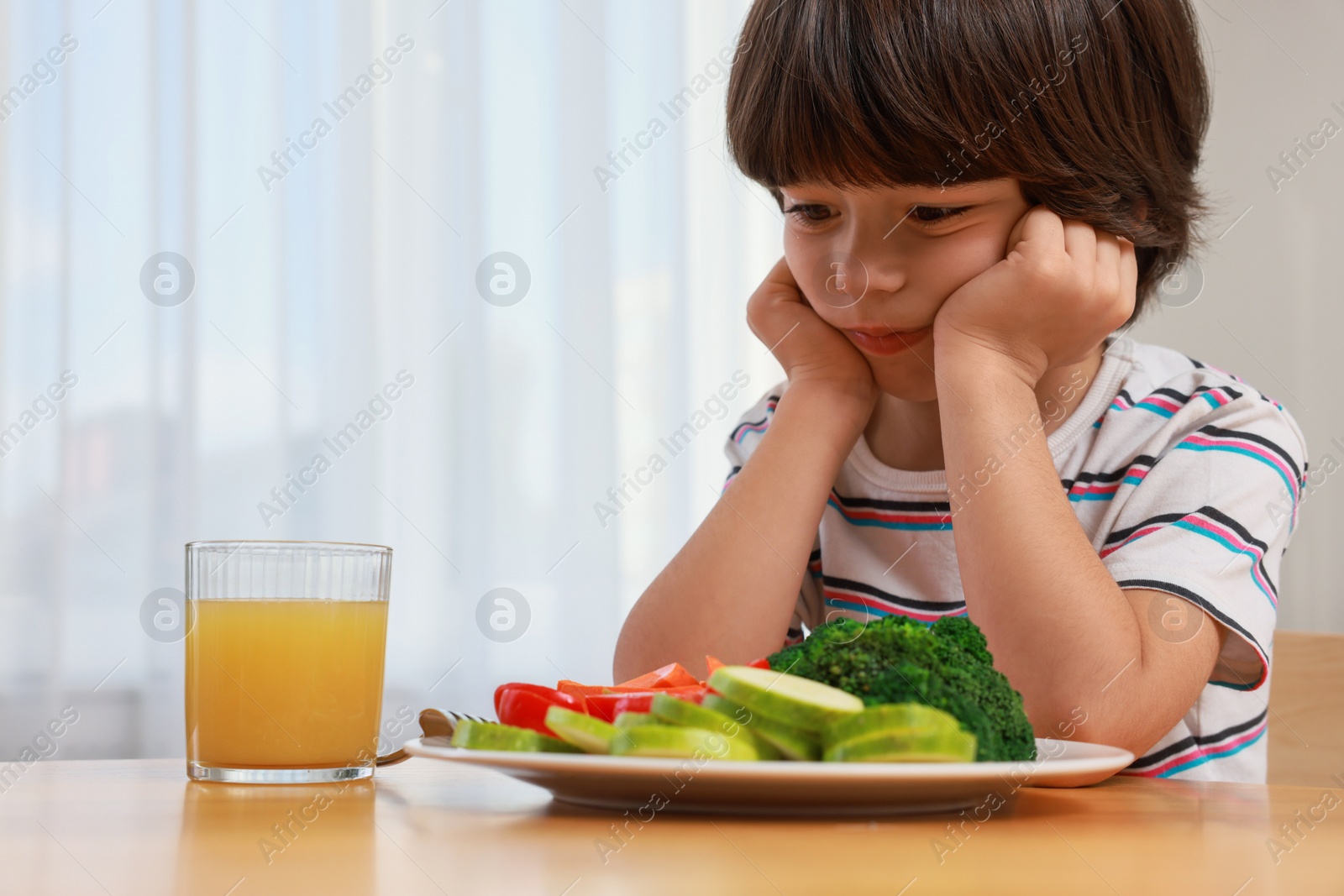 Photo of Cute little boy refusing to eat vegetables at home