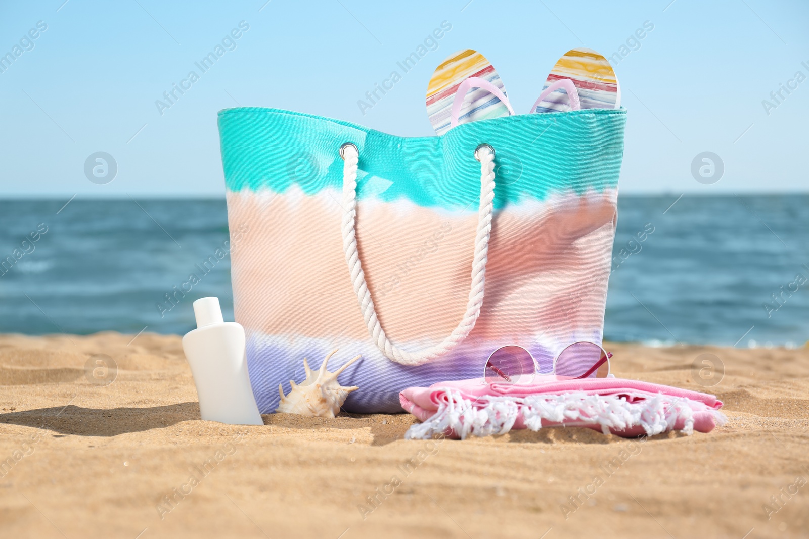 Photo of Stylish beach accessories on sand near sea