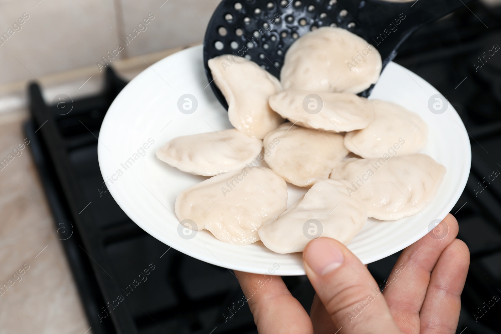 Photo of Woman putting tasty dumplings (varenyky) onto plate, closeup