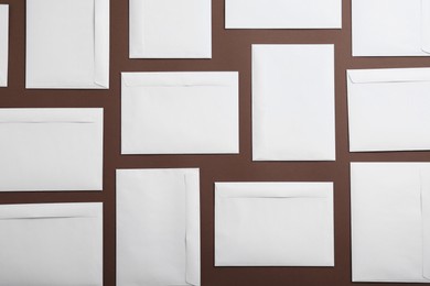 Many white paper envelopes on brown background, flat lay