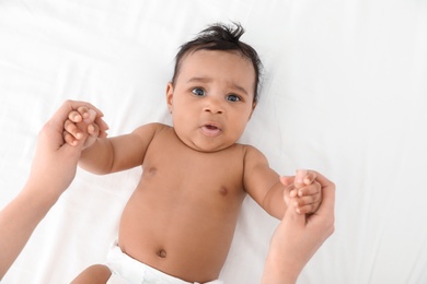 Mother and her cute child on white bed, top view. Baby massage and exercises