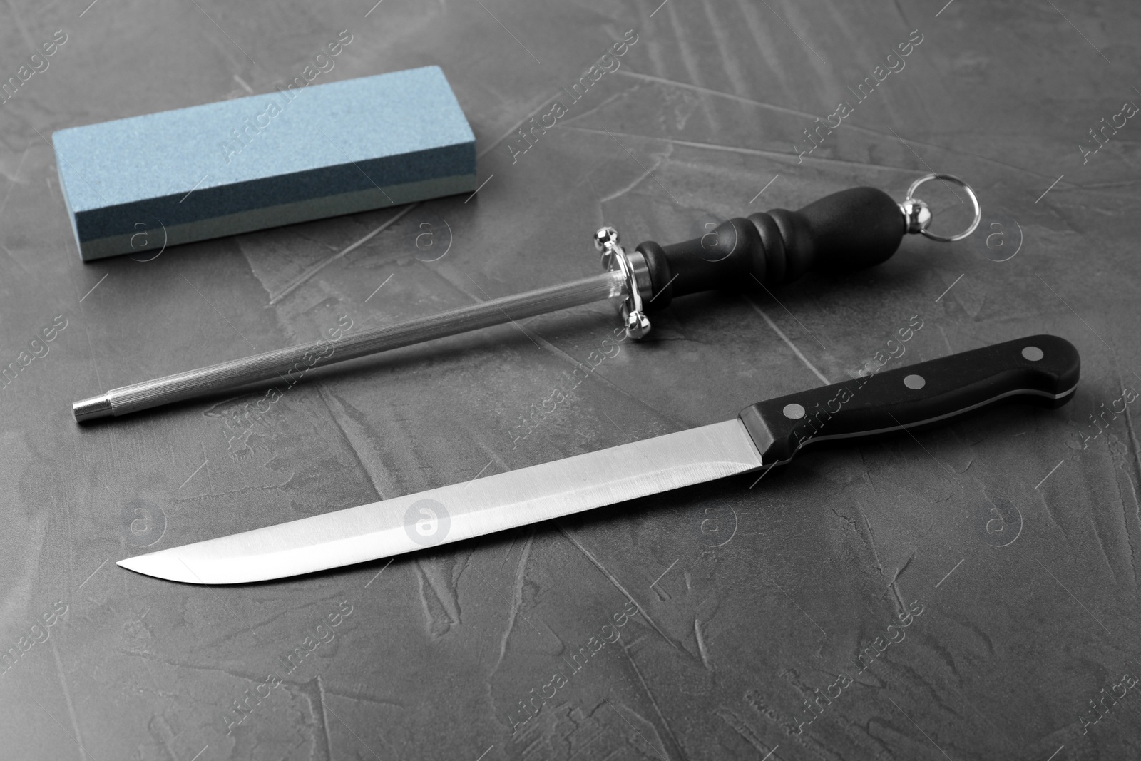 Photo of Knife and different sharpeners on grey background