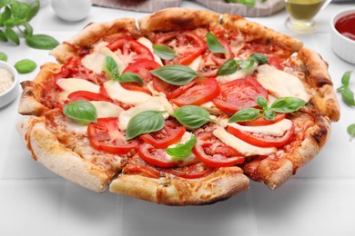 Photo of Delicious Caprese pizza on white tiled table, closeup