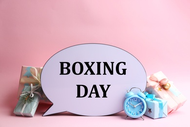 Photo of Speech bubble with phrase BOXING DAY and Christmas decorations on light pink background