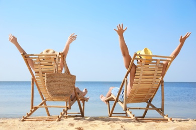 Photo of Young couple relaxing in deck chairs on beach