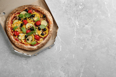 Tasty vegetable pizza in cardboard box on light grey table, top view. Space for text