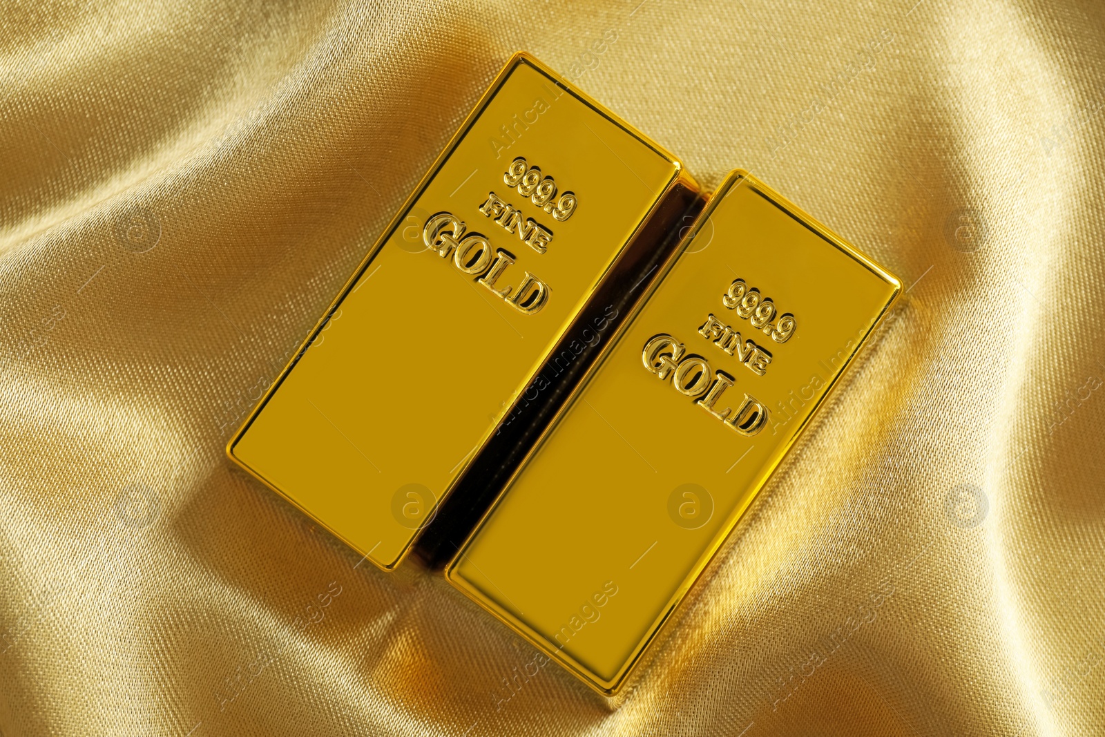 Photo of Gold bars on shiny silk fabric, flat lay