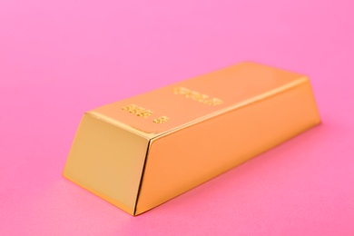 Photo of Precious shiny gold bar on color background