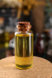 Bottle with herbal essential oils on blurred background, closeup