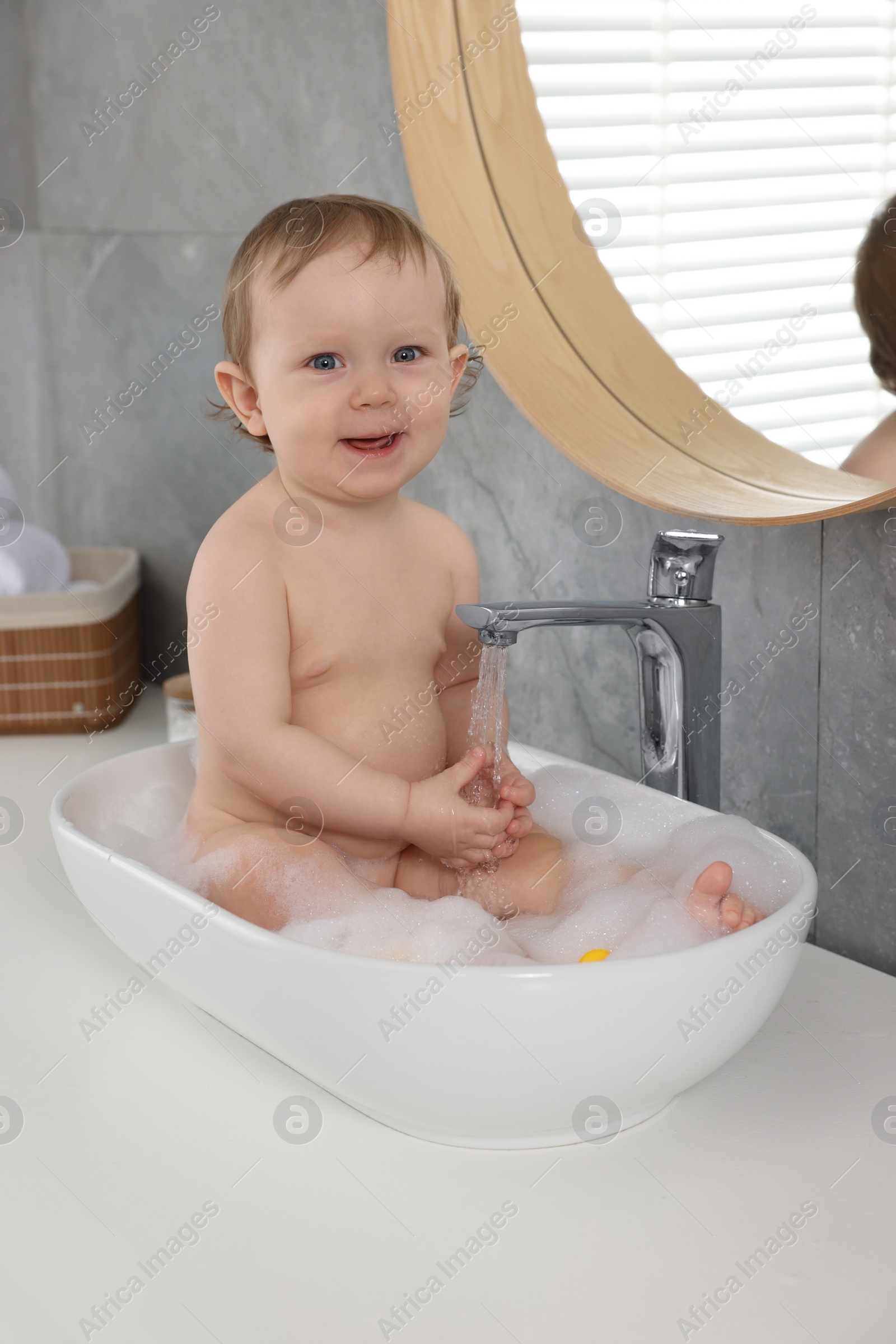 Photo of Cute little baby bathing in sink at home