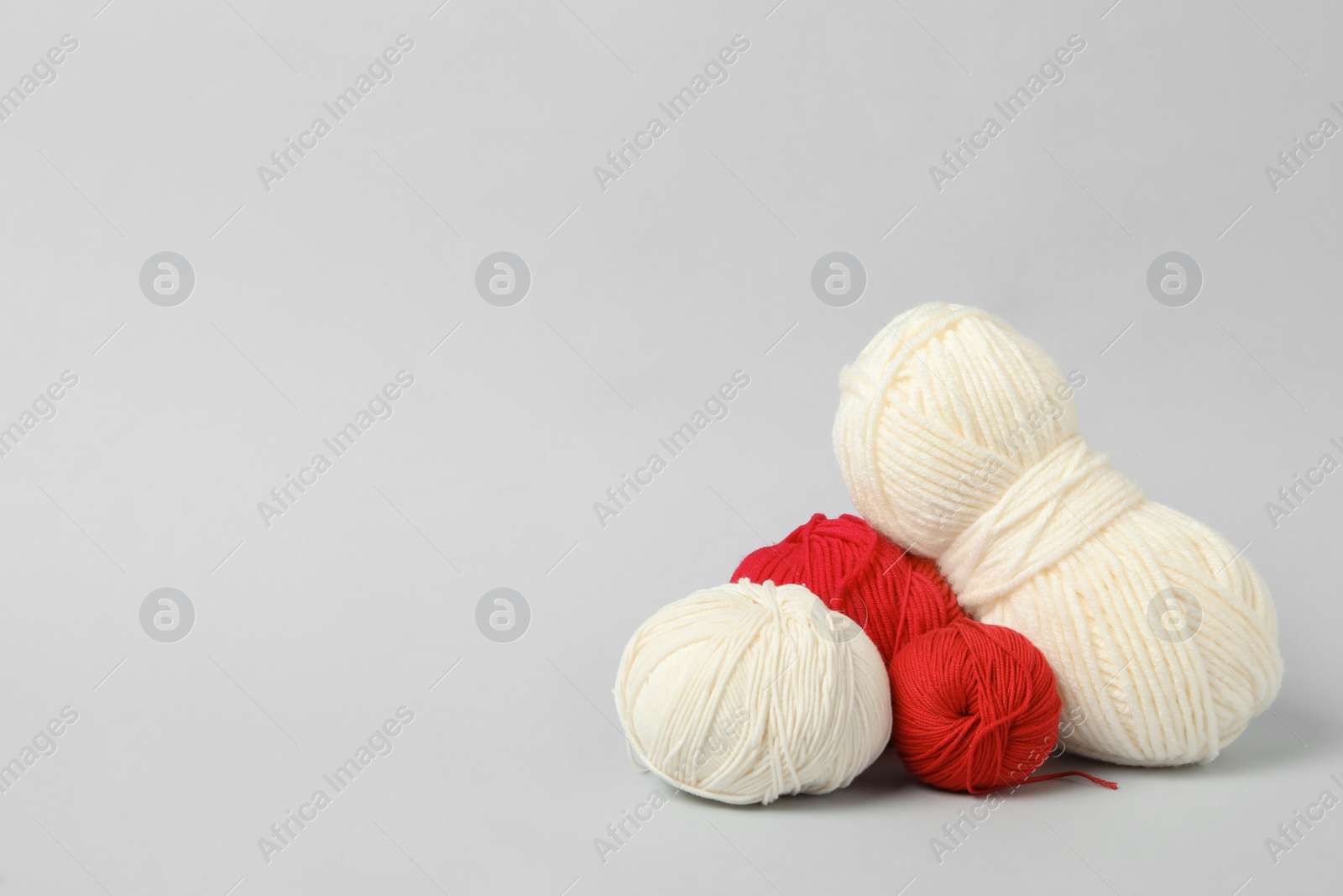 Photo of Soft woolen yarns on white background, space for text