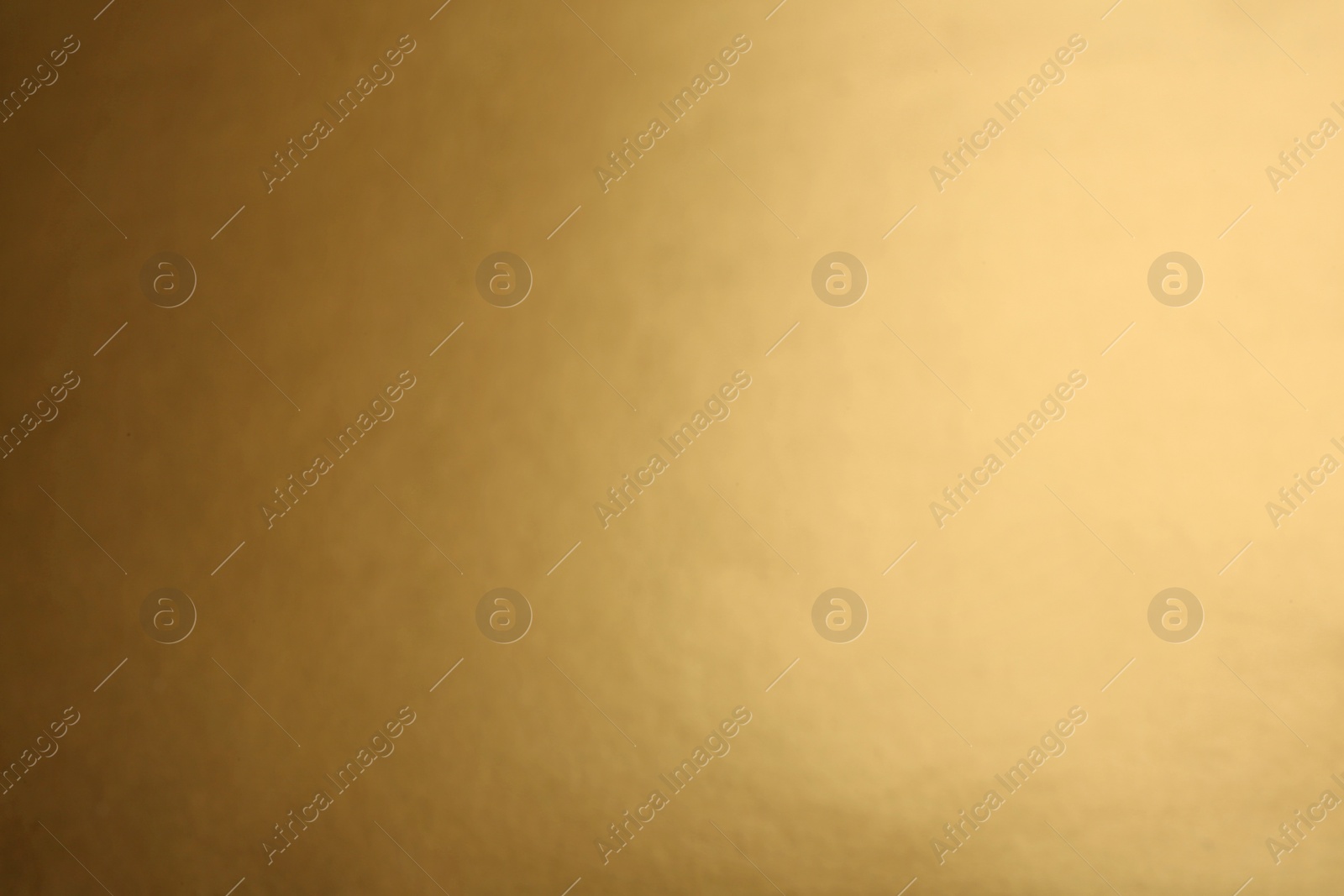 Photo of Blurred view of plain golden surface as background