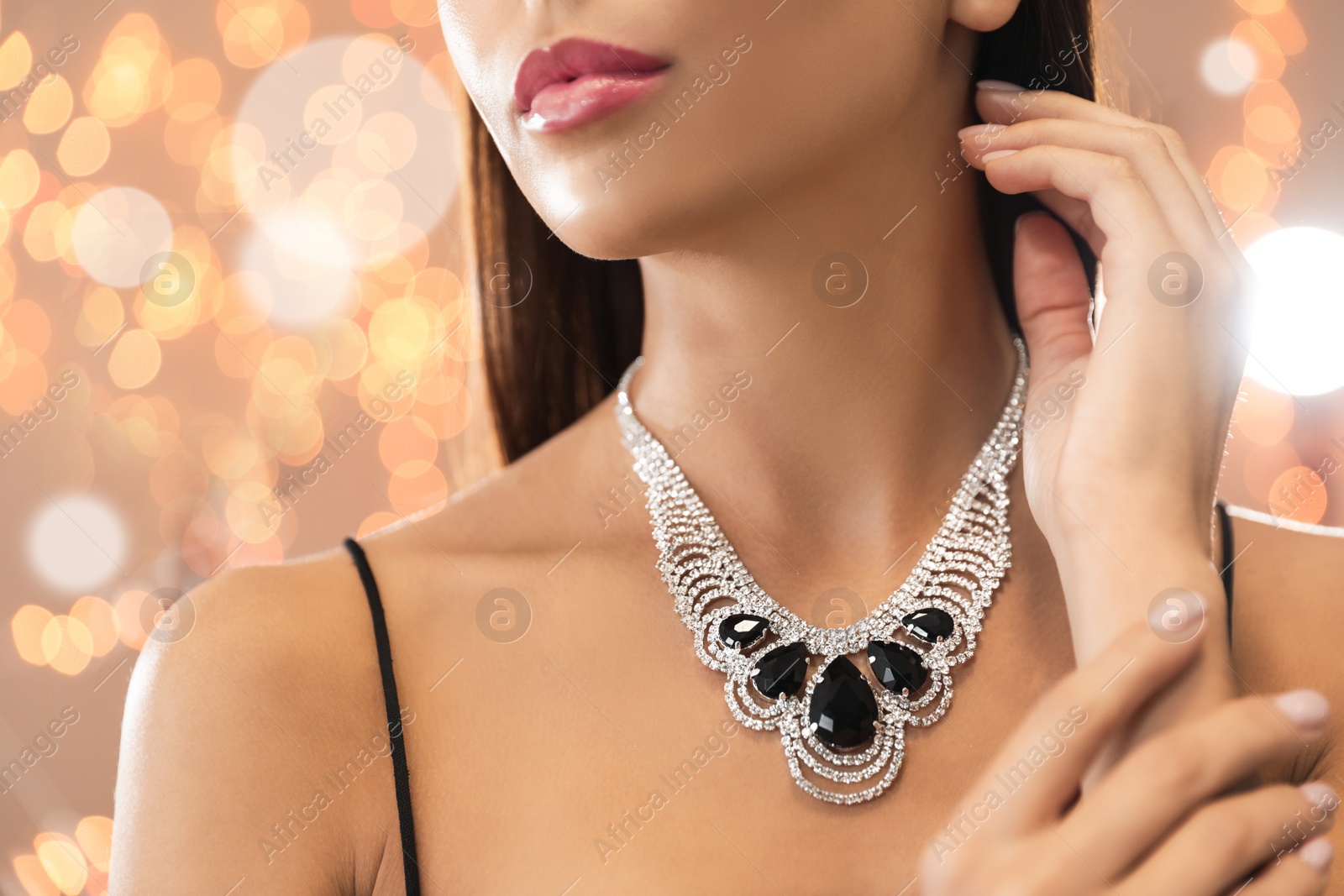 Photo of Beautiful young woman with elegant jewelry against defocused lights, closeup