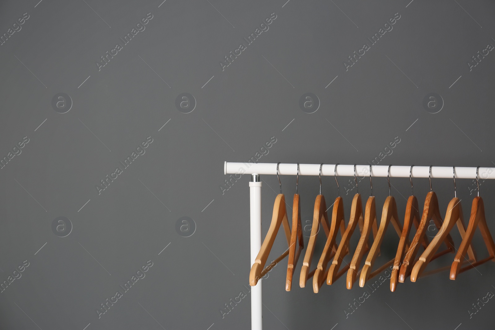 Photo of Clothes rail with wooden hangers on gray background