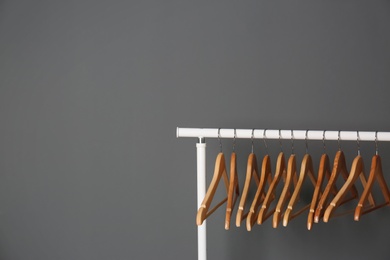 Photo of Clothes rail with wooden hangers on gray background