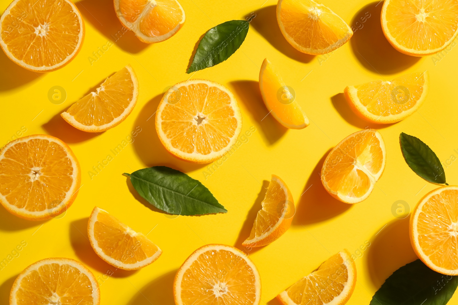 Photo of Fresh ripe oranges with green leaves on yellow background, flat lay