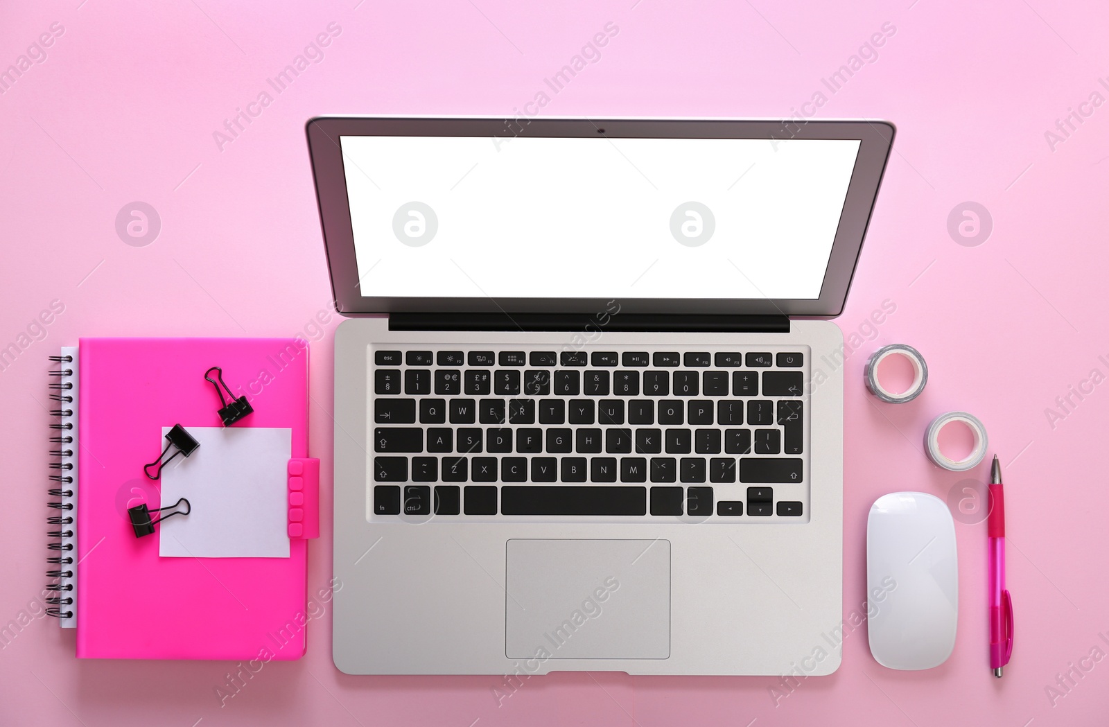 Photo of Modern laptop and office stationery on pink background, flat lay