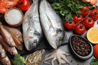 Fresh fish and different seafood on grey table, top view