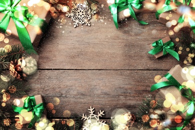 Image of Frame of gift boxes and Christmas decorations on wooden table, flat lay. Space for text