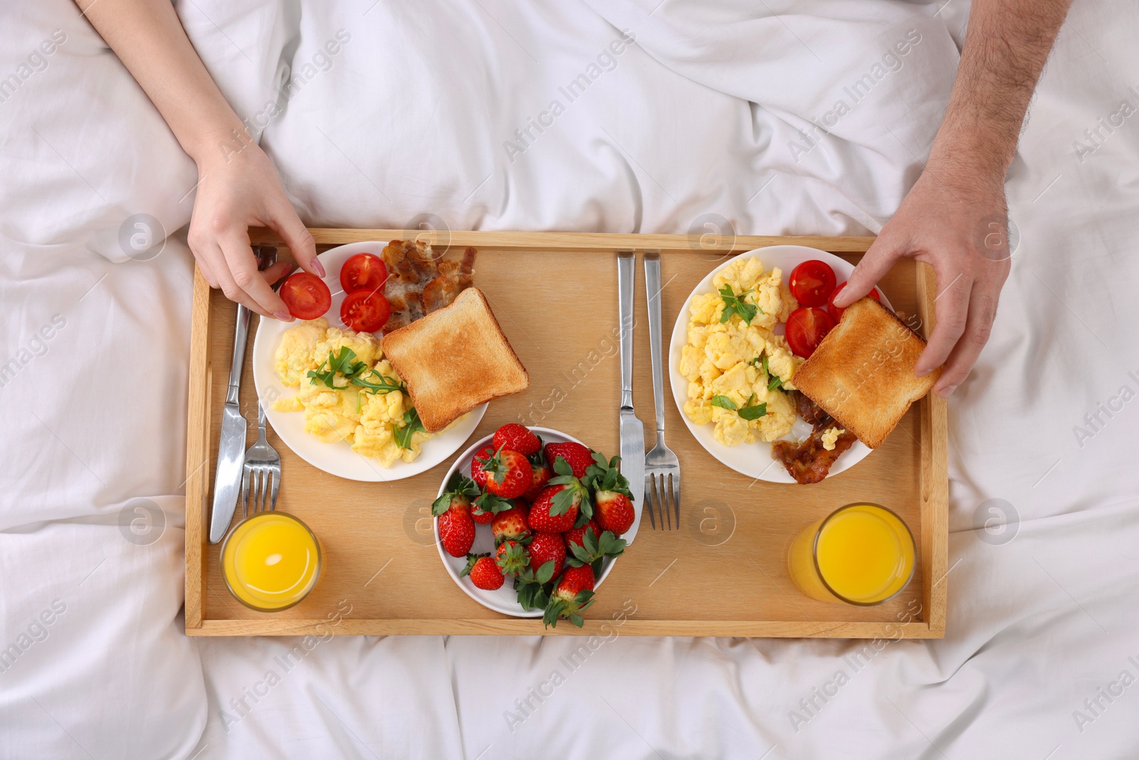 Photo of Couple eating tasty breakfast on bed, top view