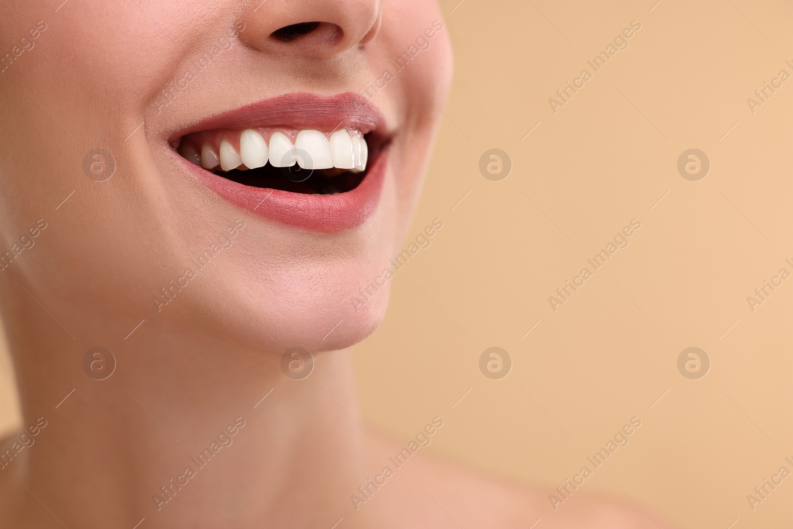 Photo of Woman with beautiful lips smiling on beige background, closeup. Space for text