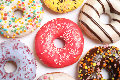 Delicious glazed donuts on white background, flat lay