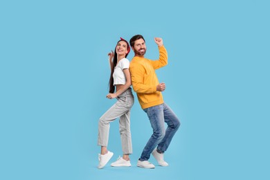 Photo of Happy couple dancing together on light blue background