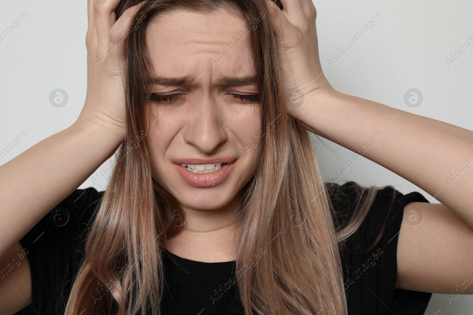 Photo of Desperate young woman on light background. Stop violence